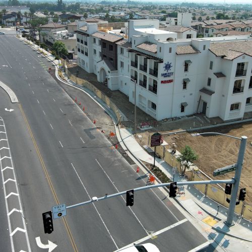 Aerial view of a newly constructed building beside a multi-lane road with traffic lights and some ongoing construction work.