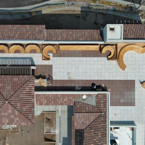 The image shows an aerial view of a building with a patterned, tiled roof and an elaborate rooftop skatepark or path design.