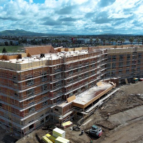 The image shows a large building under construction with scaffolding and construction materials surrounding the structure.