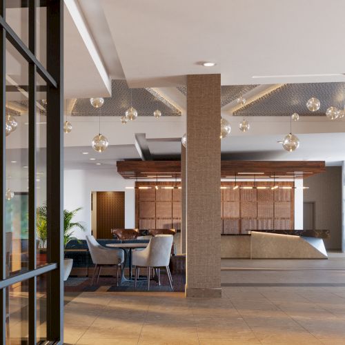 The image shows a modern lobby with glass walls, elegant lighting, seating areas, and a reception desk in a spacious setting.